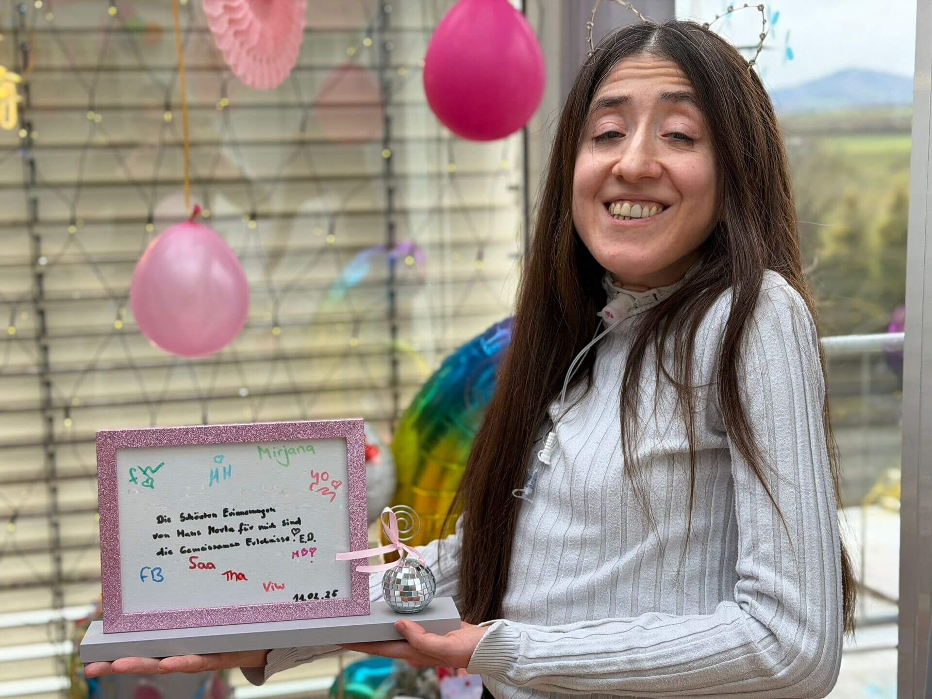 Eine Frau lächelt glücklich in einer festlich geschmückten Intensivpflege Wohngemeinschaft mit einem bunten Ballon.